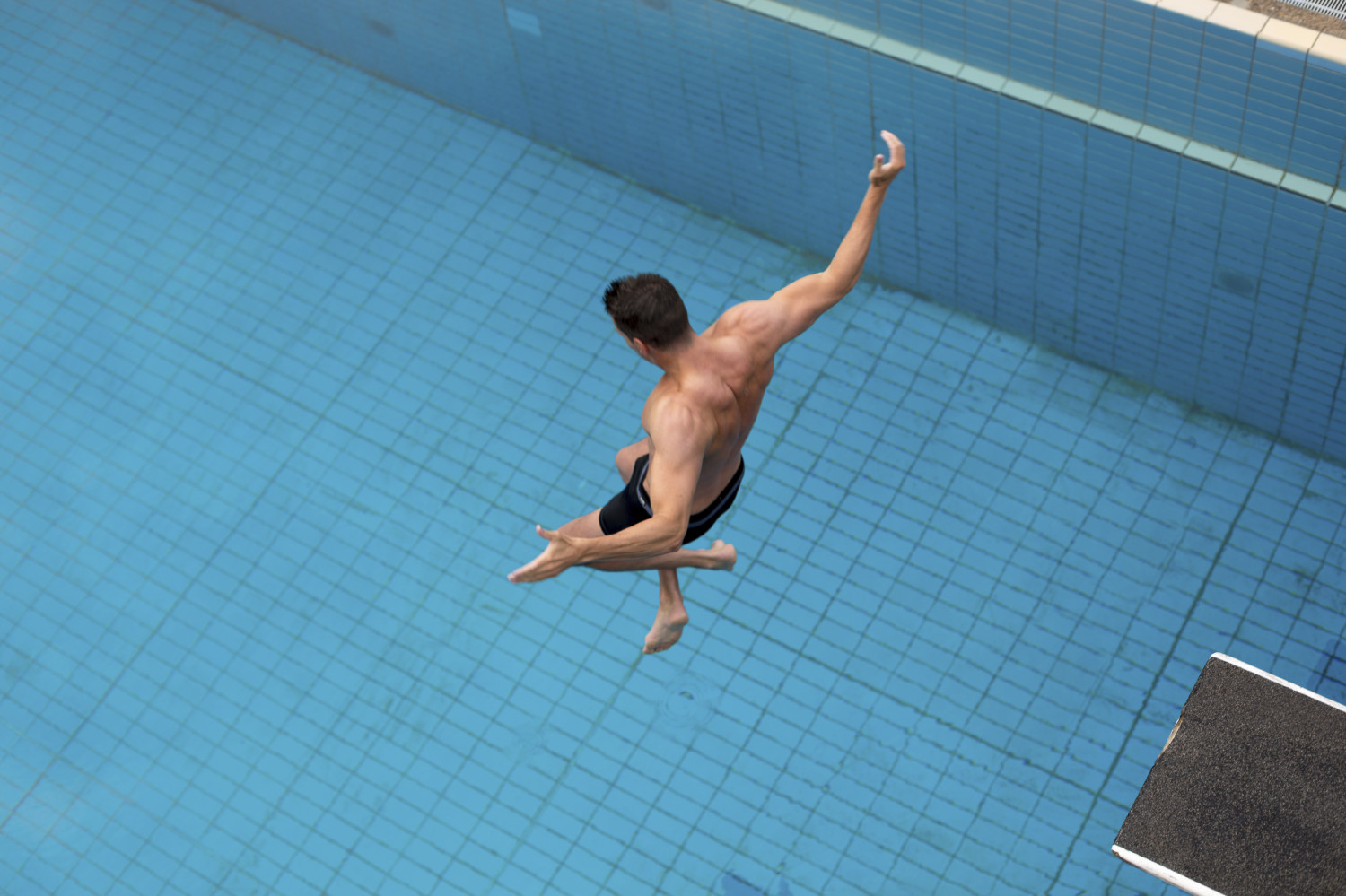 Man jumps from diving board at swimming pool